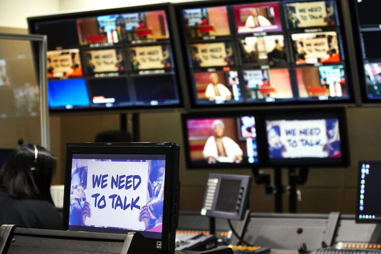 Television screens showing "We Need to Talk" panelists in a studio