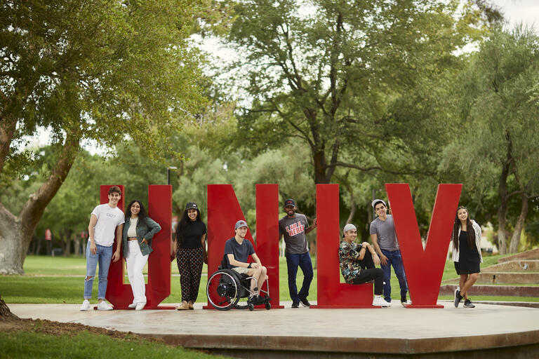 UNLV students outdoors standing amidst large red UNLV letters