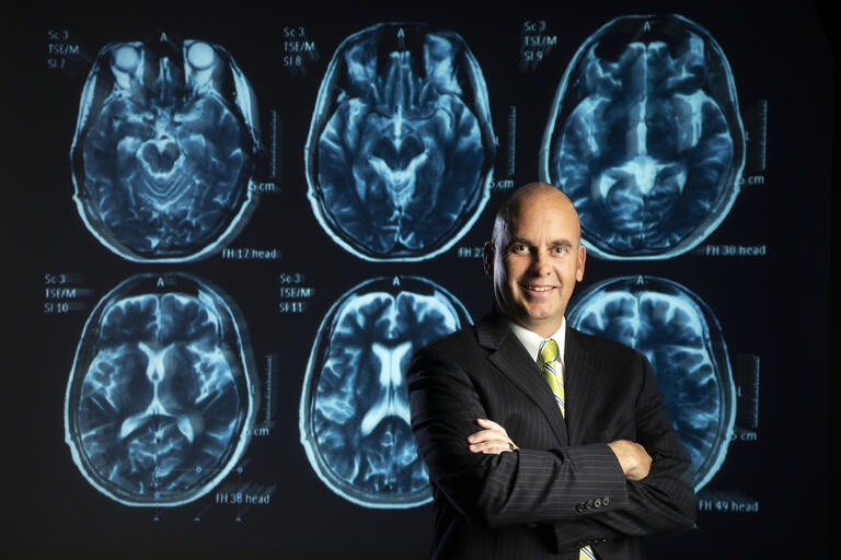 A portrait of Jefferson Kinney in front of a brain scan.