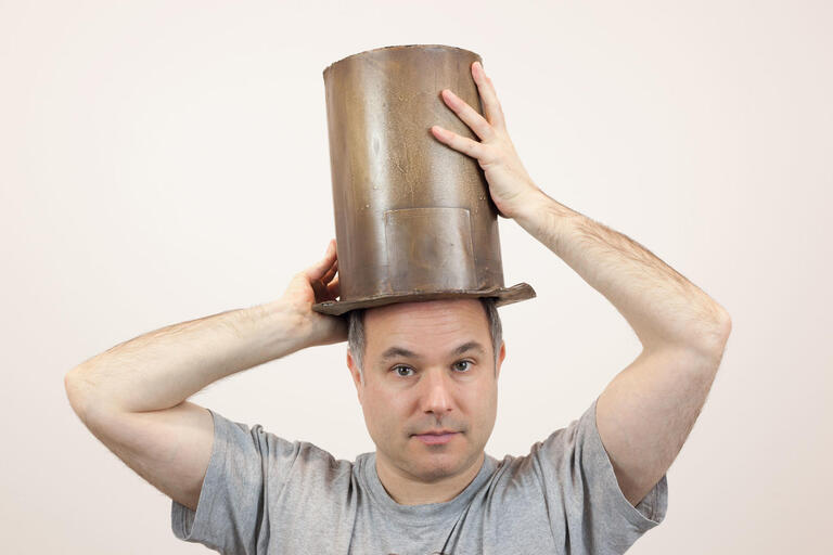 man balancing a top hat on top of head