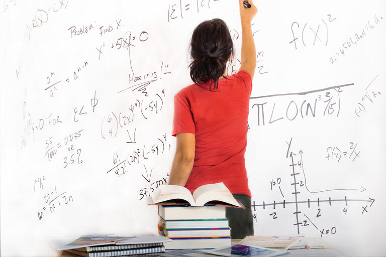 Woman writing math formula on a white board