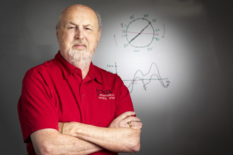 A portrait of Bill Speer, director of UNLV's Math Learning Center, standing in front of a white board.