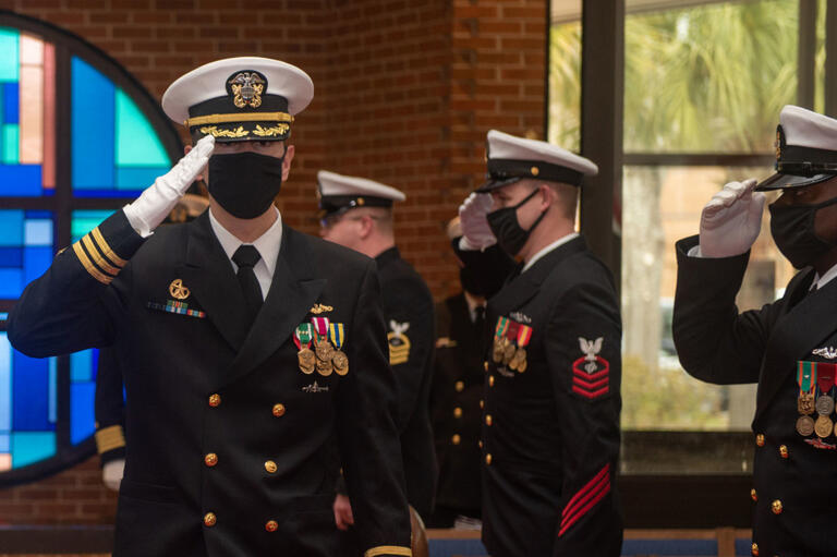 Navy Commander Stephen Col, facing camera in uniform and saluting