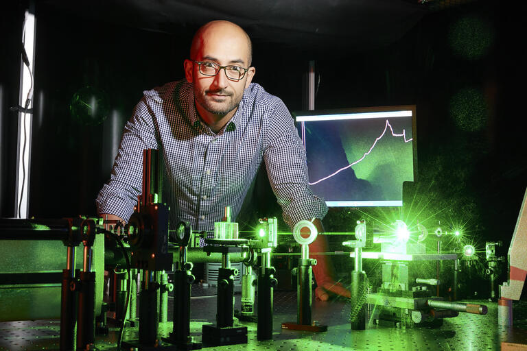 Physicist standing over table with green laser beams
