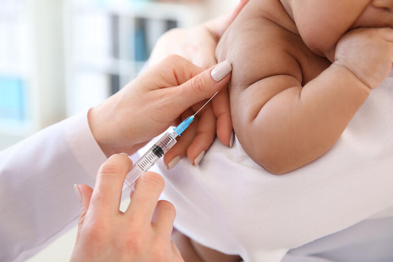 A health care provider administers a vaccination to a baby.