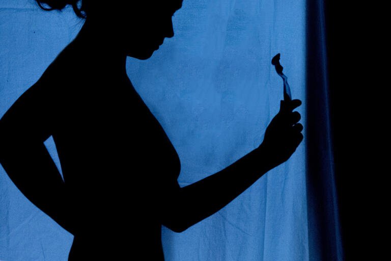 silhouette of woman holding razor against blue background