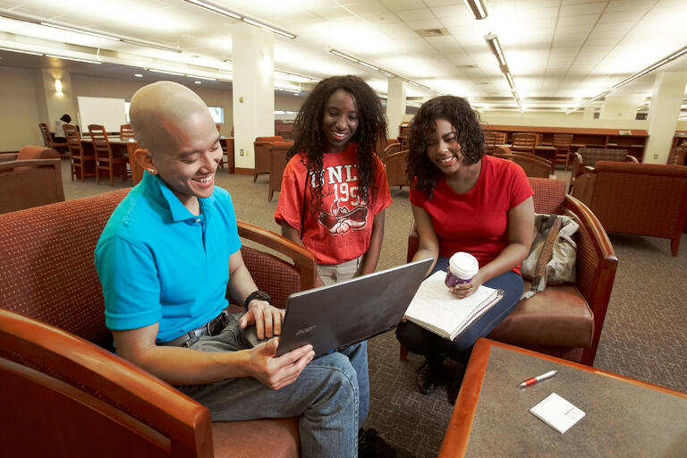 students sitting in chairs looking at a laptop