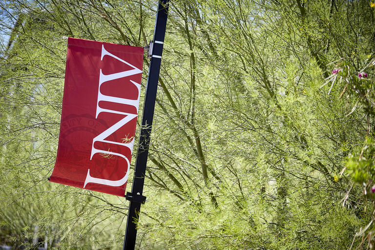 Banner with UNLV logo in front of green foliage