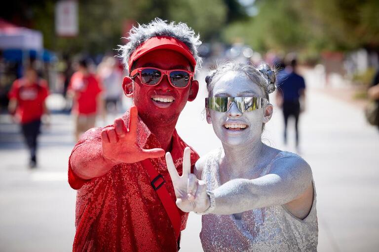Two student covered in red and silver body paint posing for a photo