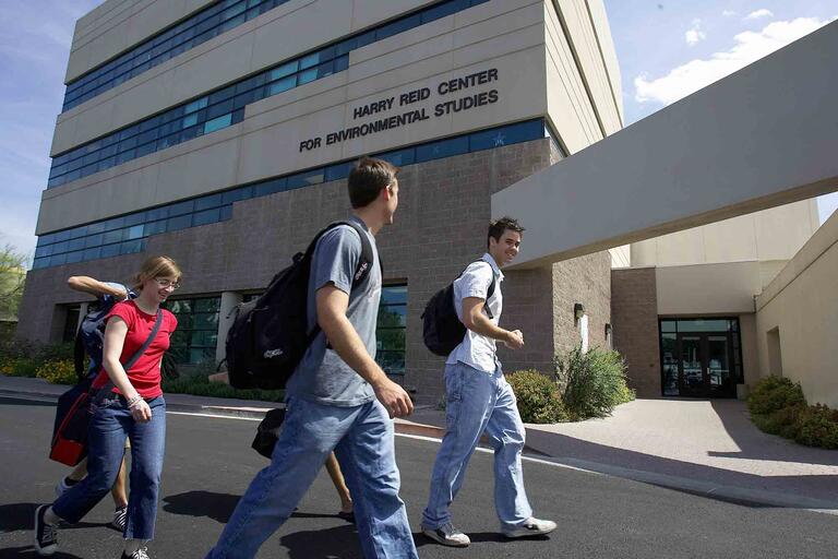 Three students walk past the Harry Reid Center building