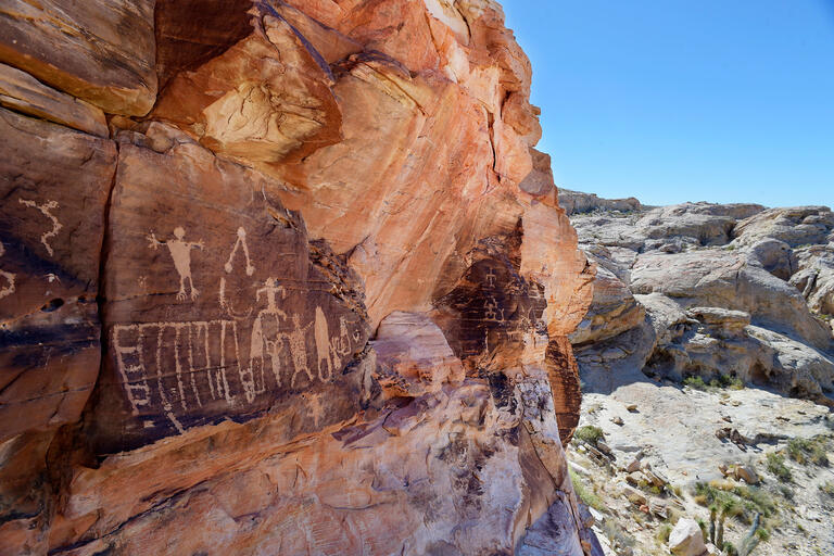 Petroglyph engravings in the side of a rock formation in the desert.