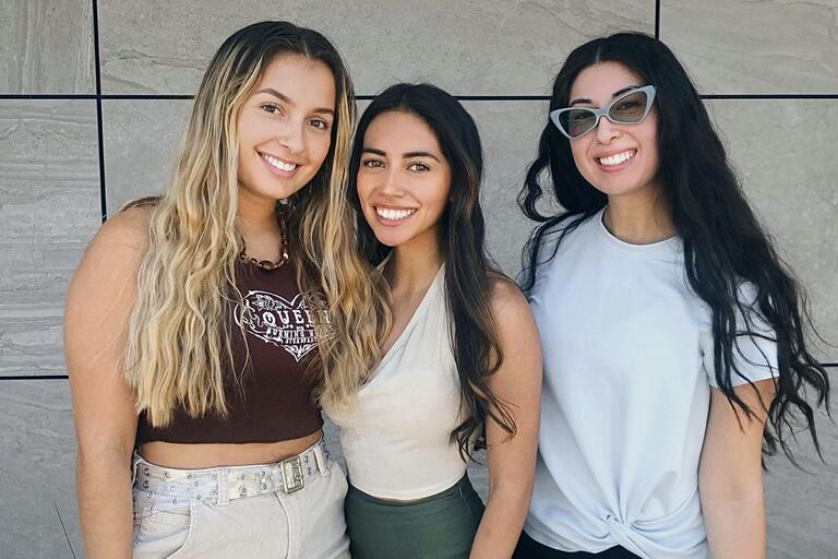 three students pose side by side
