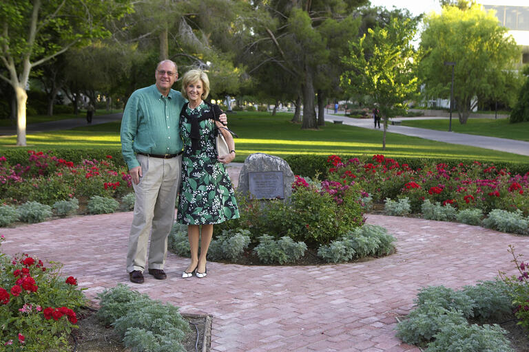 a man and woman posing in a formal garden