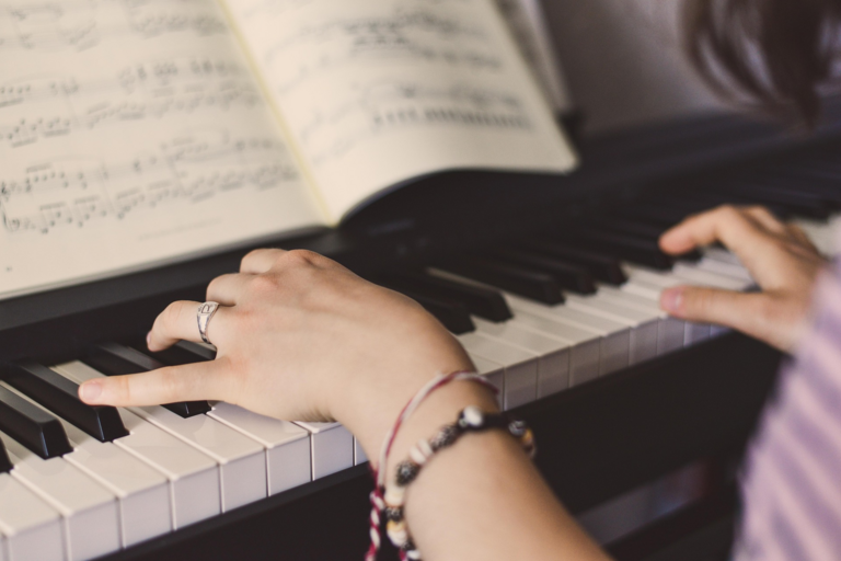 Photo of woman's hands with bracelets playing the piano.