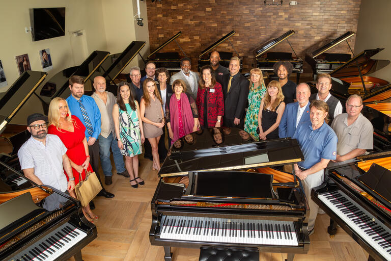 Faculty surrounding the 25 new pianos donated to UNLV