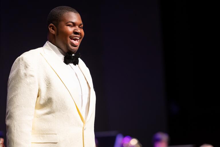 African American singer on stage performing in a white suit