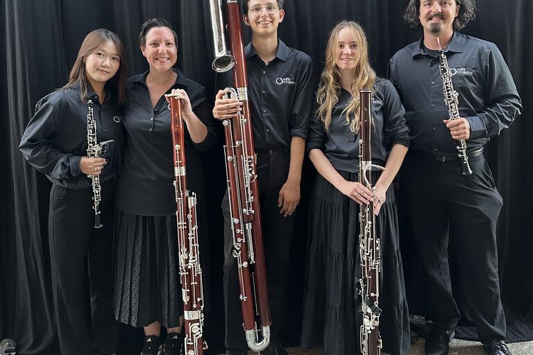 Musicians holding up their bassoons and smiling at the camera