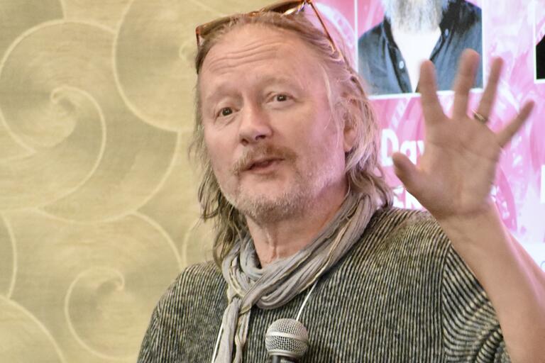 Photo of a man holding a microphone in mid sentence