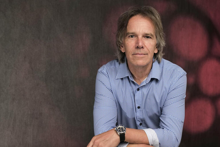 Man in blue button up shirt smiles into the camera