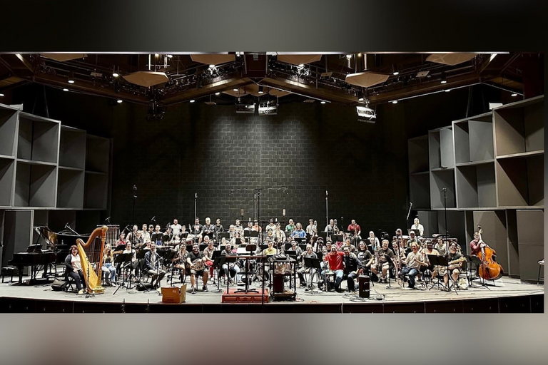 An orchestra on stage posing for a group picture