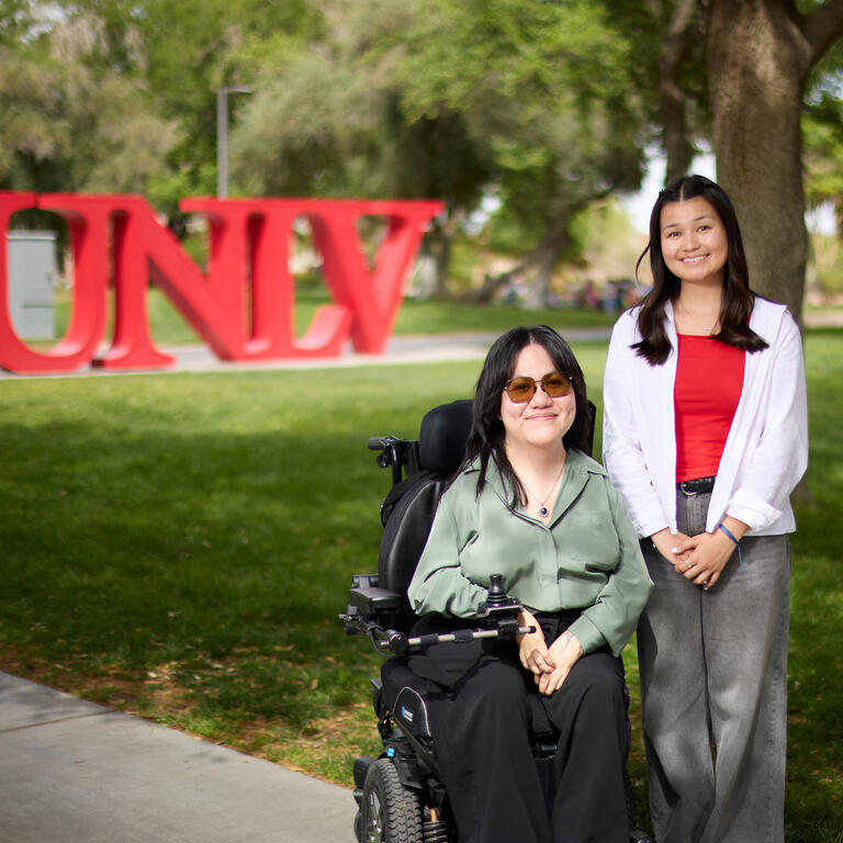 UNLV undergraduates pose for photo outdoors in front of red UNLV letters