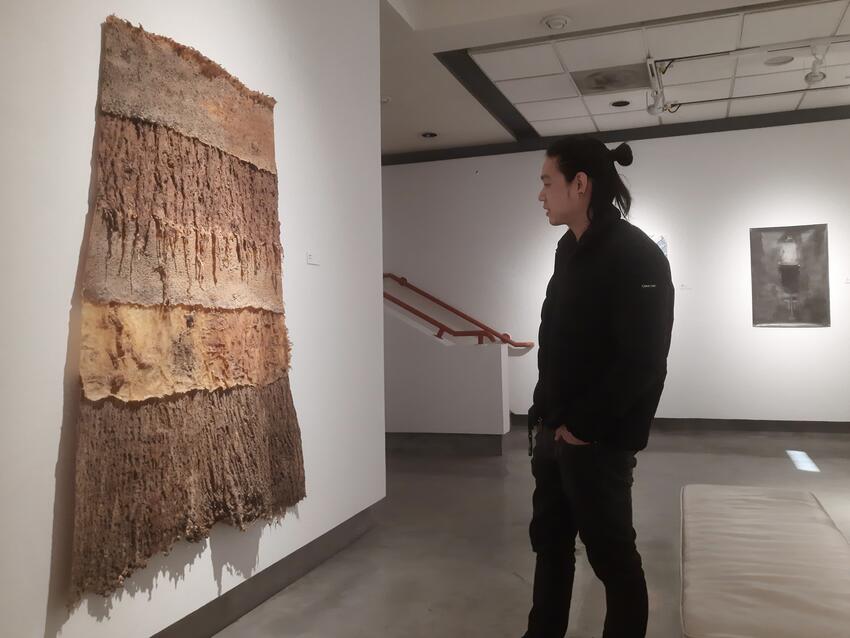 Person observing a piece of art displayed at the Donna Beam Gallery.