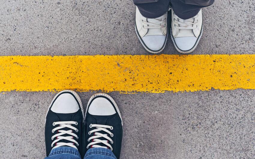 Close up of two people's shoes with a line drawing a boundary between both