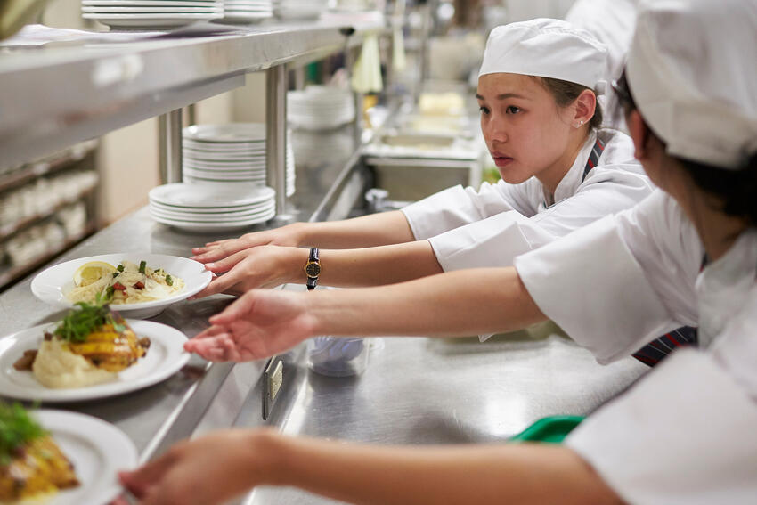 A student moving a plate of food in the kitchen