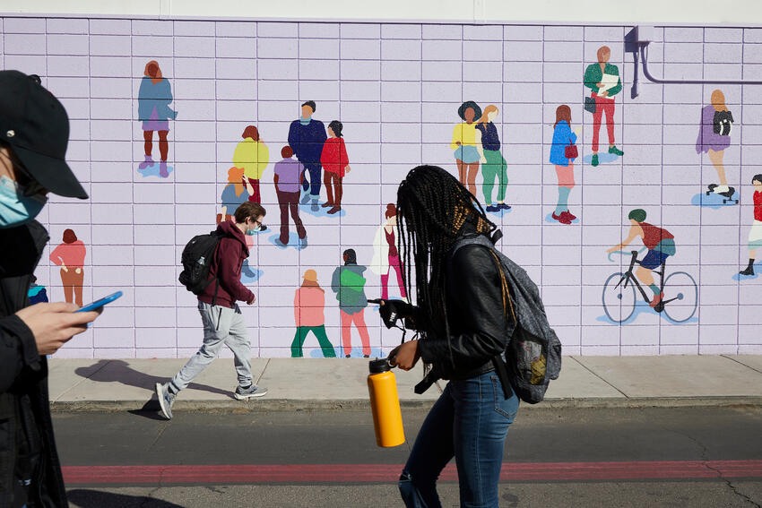 Students walking past a wall mural