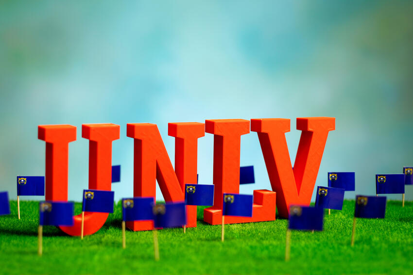 Miniature letters spelling out &quot;UNLV&quot; over a grass landscape with the Nevada state flag.