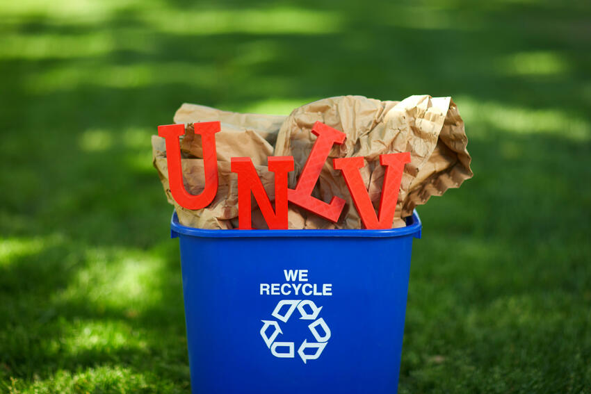 Recycling bin with a cardboard box and "UNLV" letters