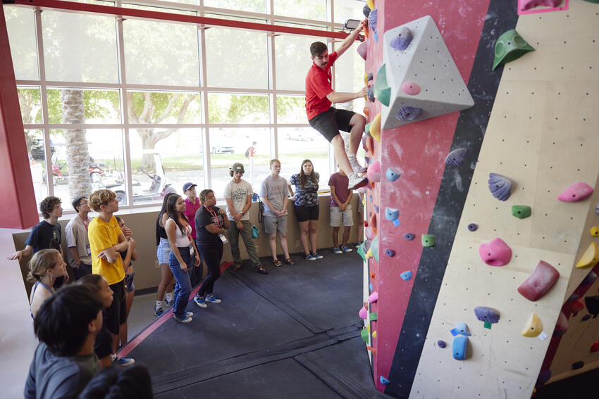 Instructor demonstrating how to use the climbing wall during a bouldering workshop.