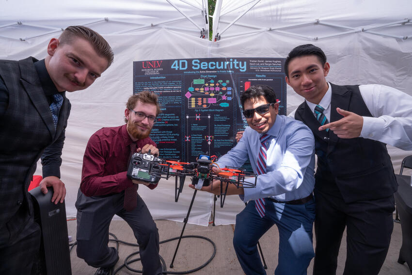 Four engineering students posing with their senior design project.