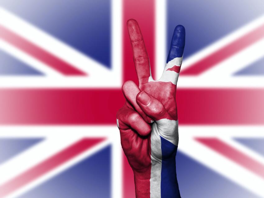 a person giving the peace symbol in front of the British flag