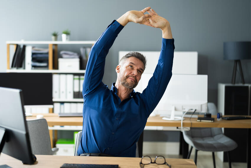 Man stretching at his computer desk