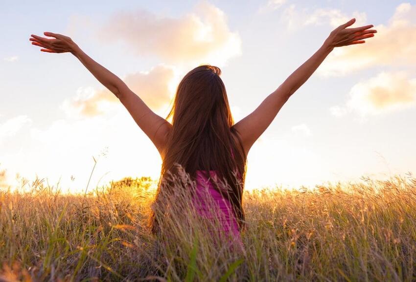 Woman raising her arms in a field