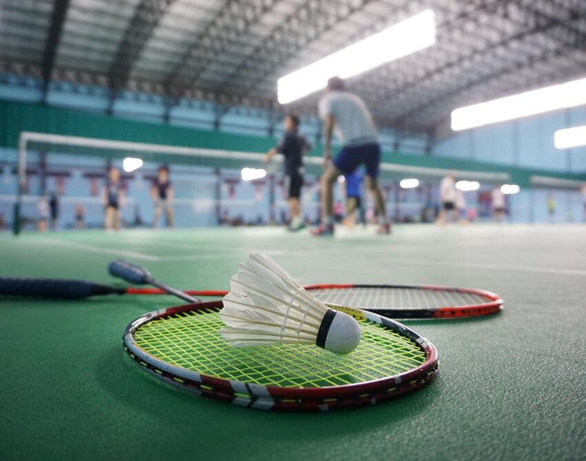 Badminton raquet and ball laying on the floor of a court.