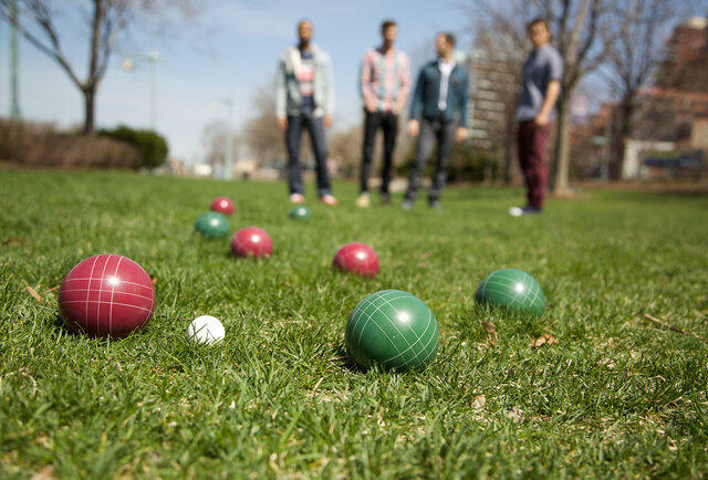 Bocce balls on the grass with players in the distance