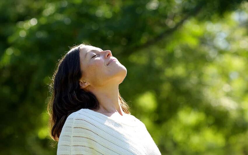 A woman meditating outside with her eyes closed