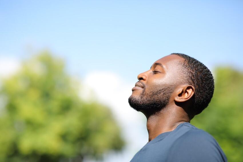 Man taking a deep breath outside