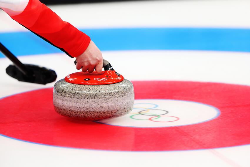 Close up of an athlete holding a curling stone