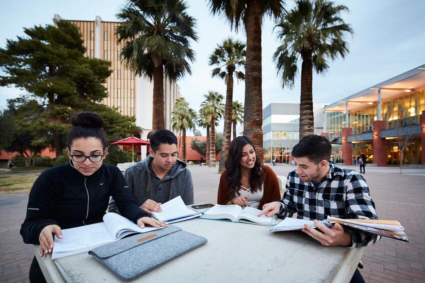 Four students sitting outside the Student Union studying.