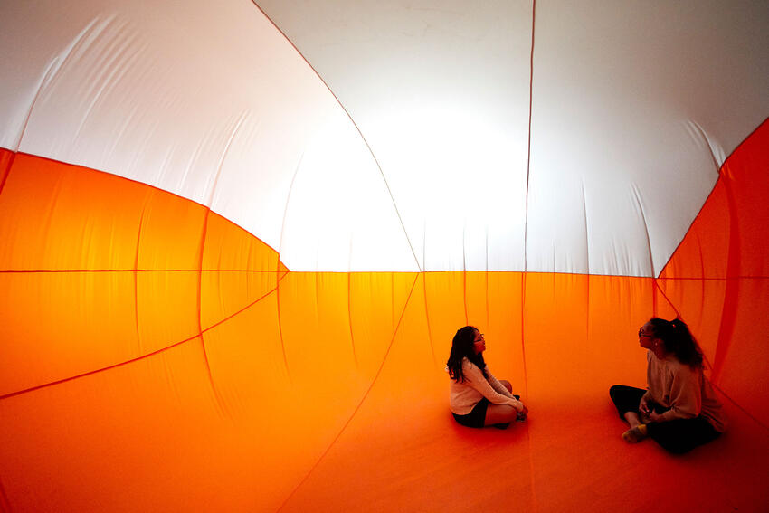 Two students sit inside an orange and white inflation