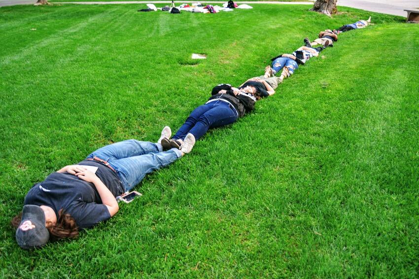 People lying in a row in the grass