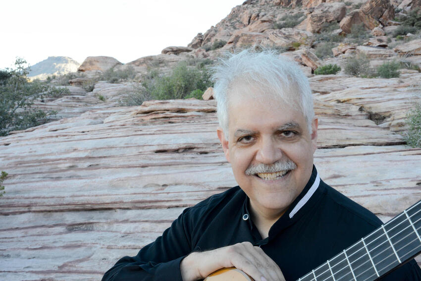 Ricardo Cobo with guitar in front of mountain