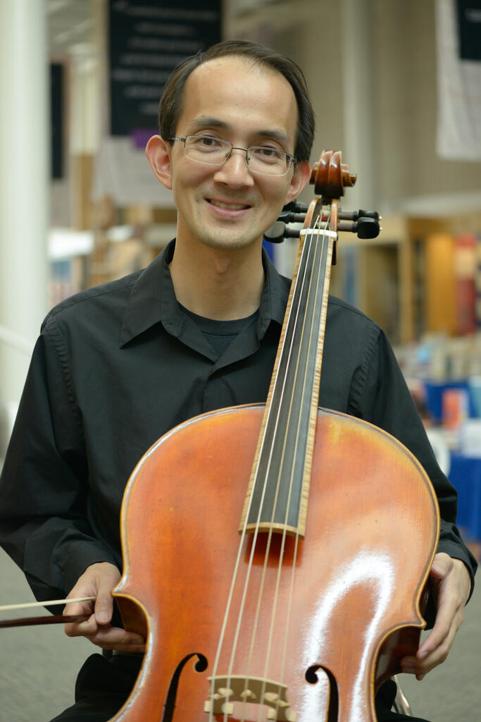 A man posing with a cello.