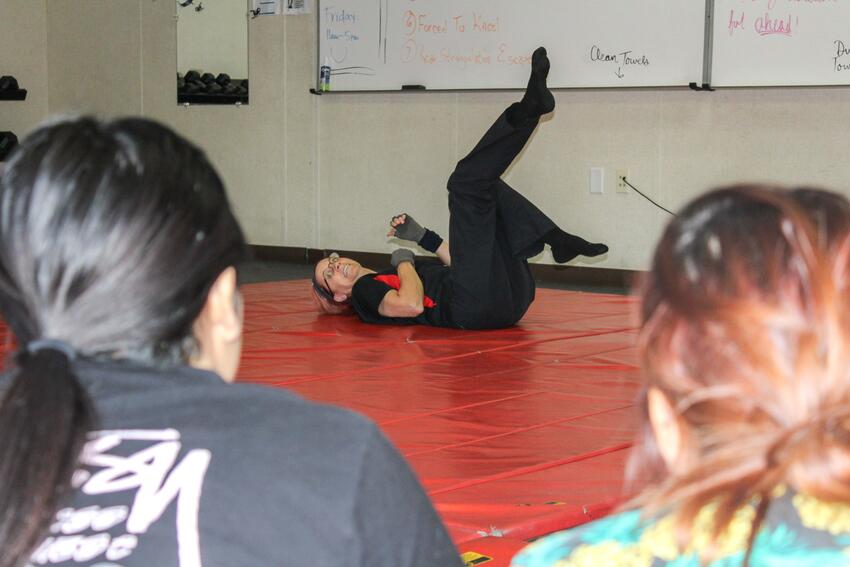 An instructor on the floor demonstrating self defense.