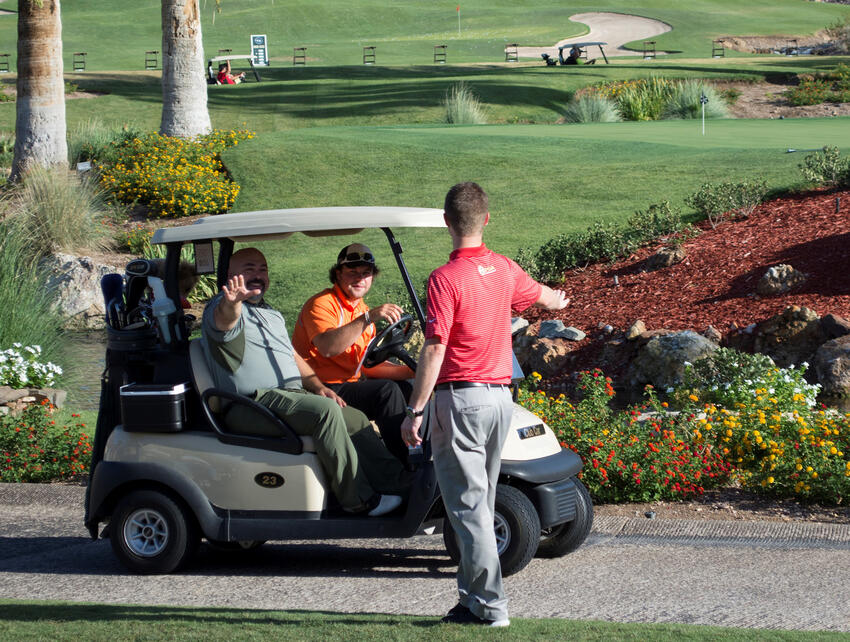 Three men with a golf cart on a golf course