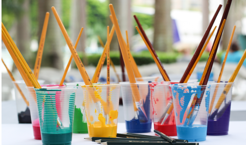 Plastic cups with paint and paint brushes