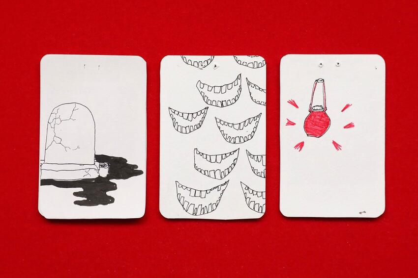 Three playing cards with art drawn on the backs.